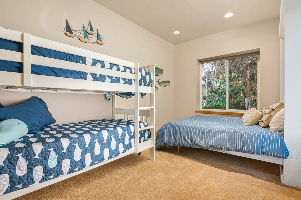 A playful bedroom designed for families, featuring bunk beds with decorative pillows, a window with a scenic view, and cheerful decor. The setup encourages shared experiences while still maintaining a sense of personal space.