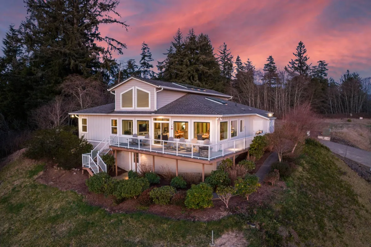 An inviting exterior view of Bay View Villa, emphasizing the large deck surrounded by trees—perfect for outdoor family gatherings or sunset s’mores after a day of adventure.