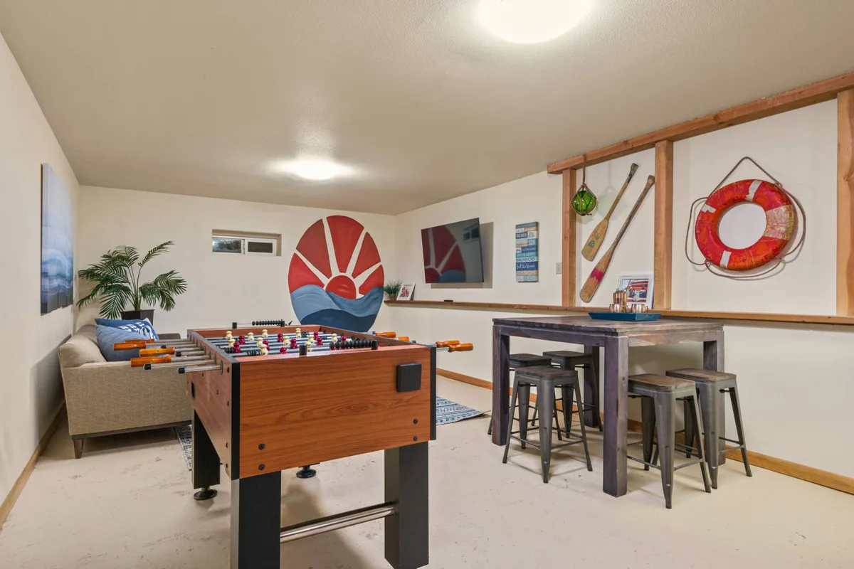 A colorful, inviting area centered around a foosball table, complemented by vibrant wall art and a wooden bar table. The space feels lively and designed for friendly competition or relaxed hangouts.