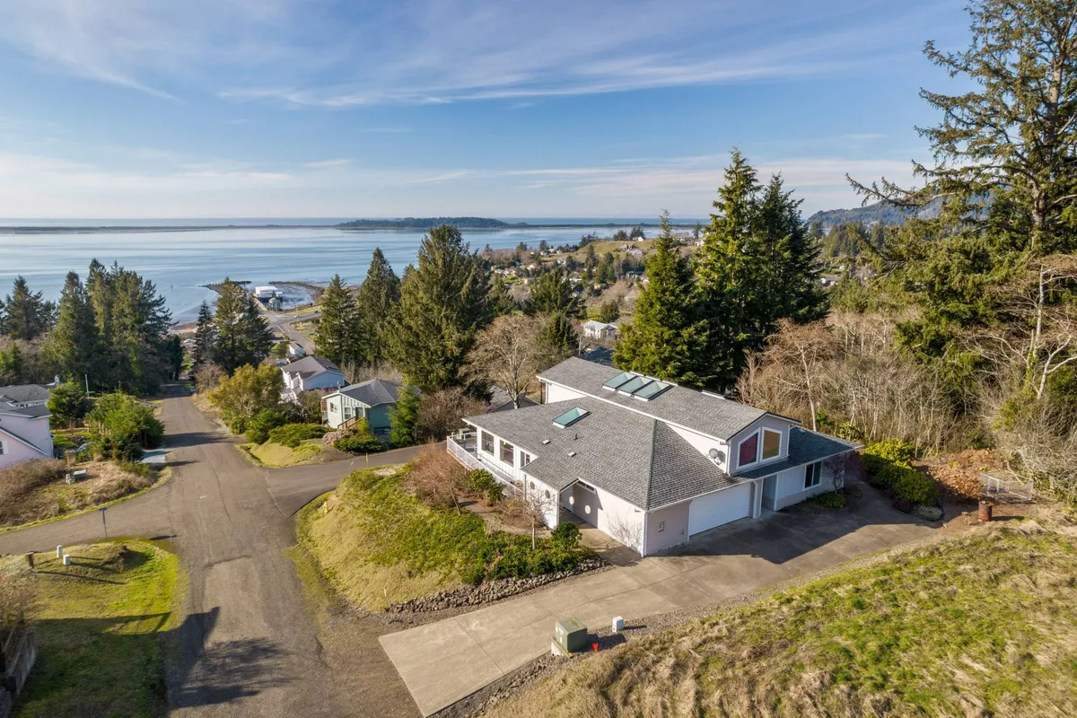 An exterior view of the home, surrounded by trees and opening onto a tranquil waterfront. The porch and water views extend the sense of communal gathering and offer a glimpse of the serene natural setting that guests can explore beyond the villa.