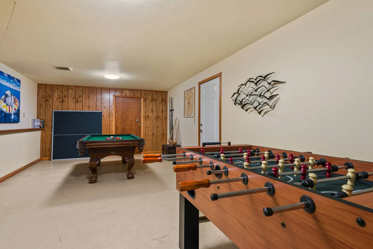Inside the villa, the dedicated game room features a full-size pool table and foosball table, with warm wood paneling and playful decor. The layout invites friendly competition and fun group interactions, directly tying into the section's focus on group entertainment.